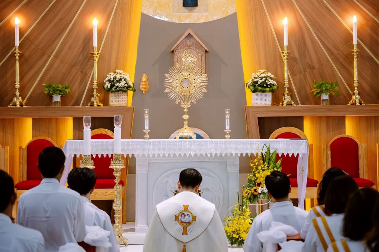 A priest leads a mass ceremony in a beautifully decorated church altar with candles.