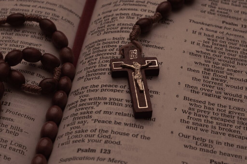 A rosary beads and crucifix resting on an open Bible displaying Psalms.